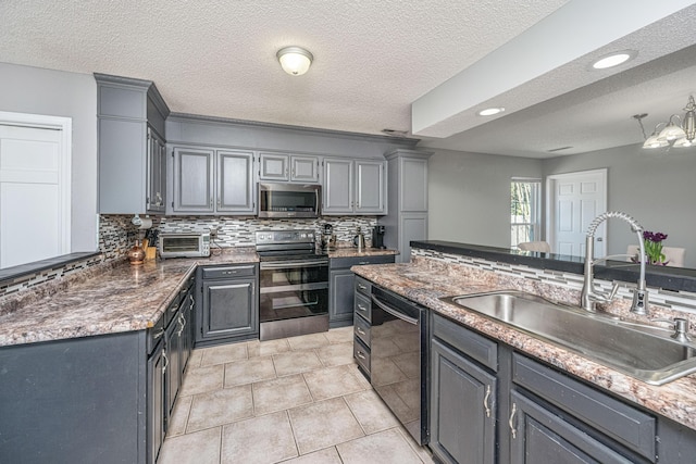 kitchen featuring appliances with stainless steel finishes, backsplash, a sink, and gray cabinetry