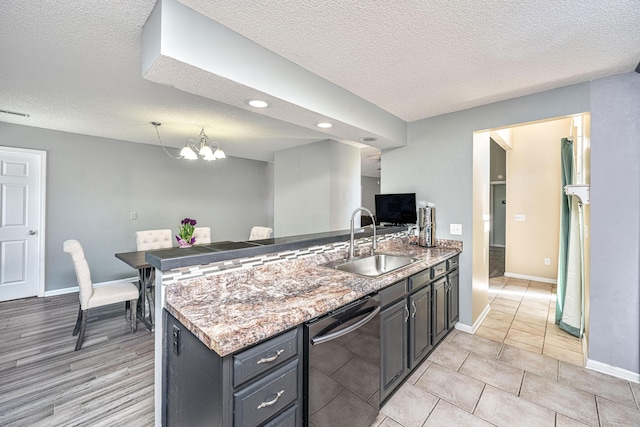 kitchen featuring a sink, a peninsula, stainless steel dishwasher, and a textured ceiling