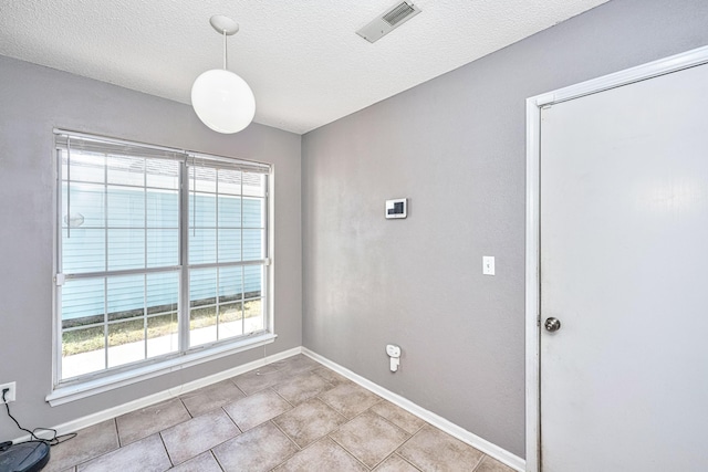 spare room with visible vents, a textured ceiling, baseboards, and tile patterned floors