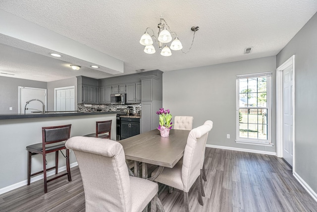 dining space with a chandelier, a textured ceiling, dark wood finished floors, and baseboards