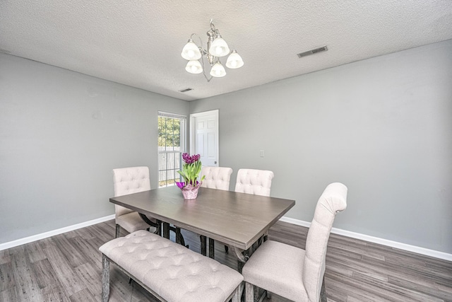 dining area featuring baseboards, a textured ceiling, visible vents, and wood finished floors