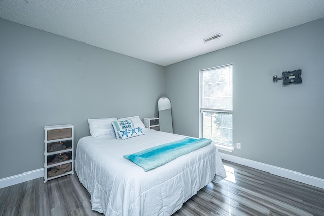 bedroom with wood finished floors, visible vents, and baseboards