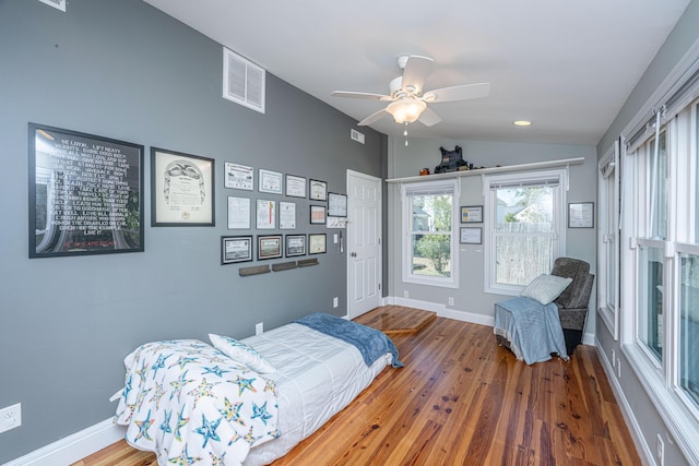 bedroom with lofted ceiling, baseboards, visible vents, and wood finished floors