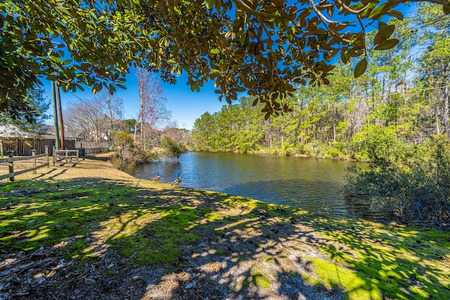 view of water feature featuring a wooded view and fence