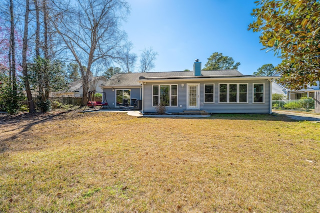 back of property with a patio area, a chimney, and a lawn