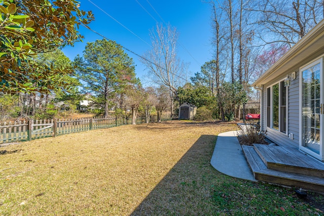 view of yard with a storage shed, an outbuilding, and a fenced backyard