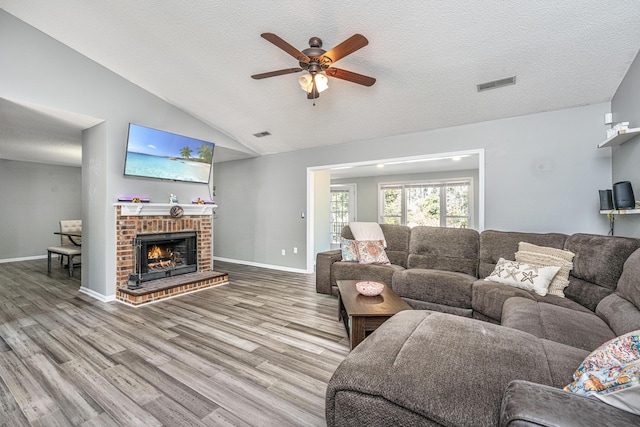 living room featuring lofted ceiling, a textured ceiling, visible vents, and wood finished floors