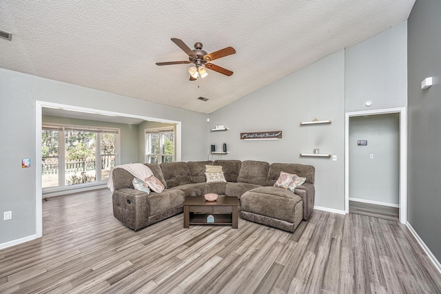 living room featuring visible vents, a ceiling fan, wood finished floors, vaulted ceiling, and a textured ceiling