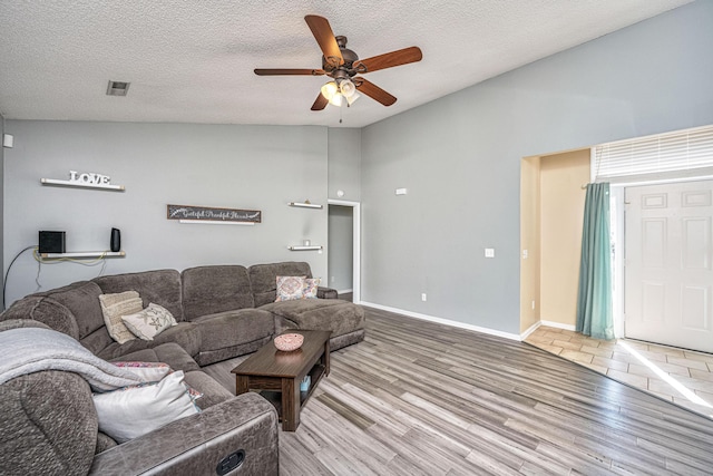 living room featuring lofted ceiling, light wood-style flooring, and a textured ceiling