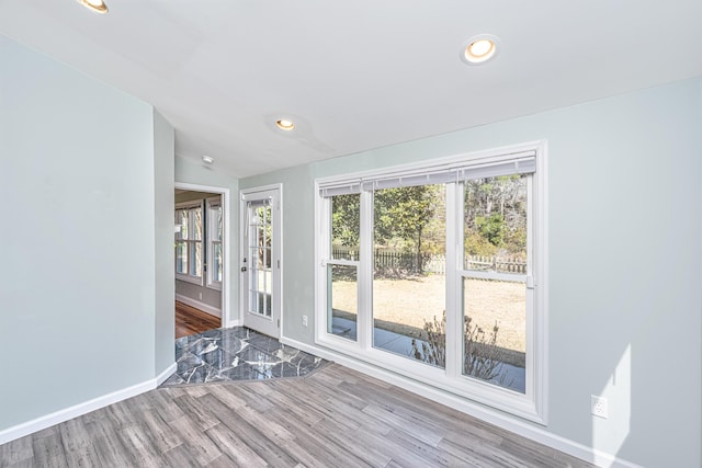 empty room with baseboards, recessed lighting, wood finished floors, and a healthy amount of sunlight