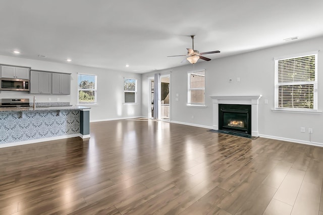 unfurnished living room with sink, ceiling fan, and dark hardwood / wood-style flooring