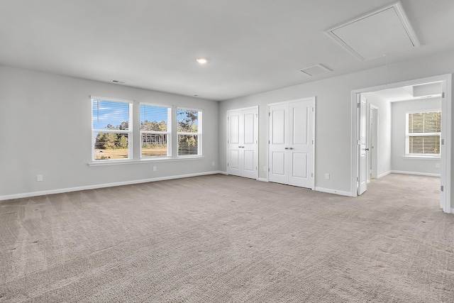 unfurnished bedroom with multiple closets and light colored carpet