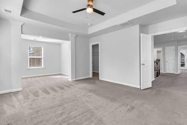 unfurnished living room with ceiling fan, carpet flooring, and a tray ceiling