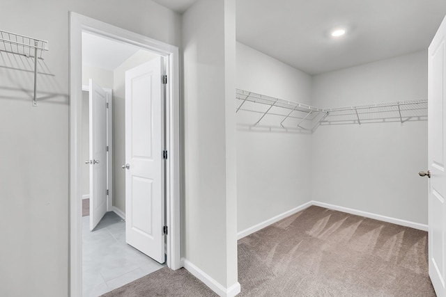 walk in closet with light colored carpet