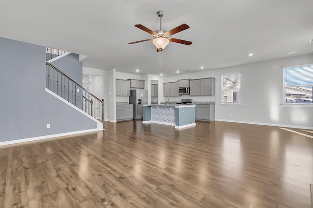 unfurnished living room featuring ceiling fan, sink, and dark hardwood / wood-style flooring