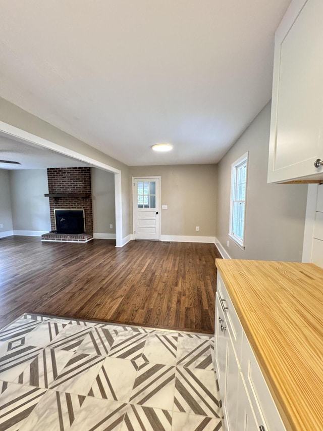 unfurnished living room with a brick fireplace and wood-type flooring