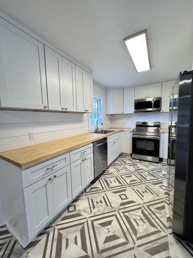 kitchen featuring white cabinetry, sink, black appliances, and wooden counters