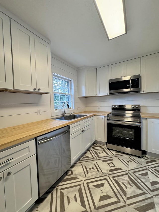 kitchen featuring white cabinetry, stainless steel appliances, sink, and butcher block countertops