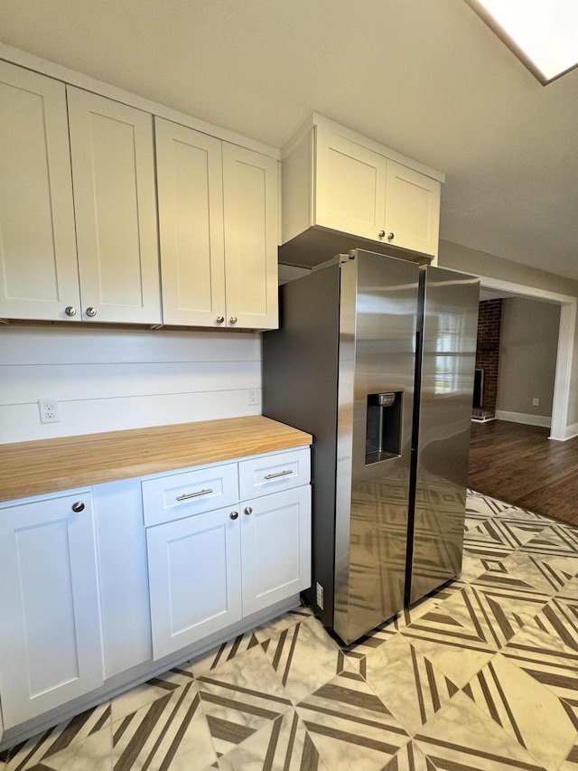 kitchen with white cabinetry, stainless steel fridge with ice dispenser, and wood counters