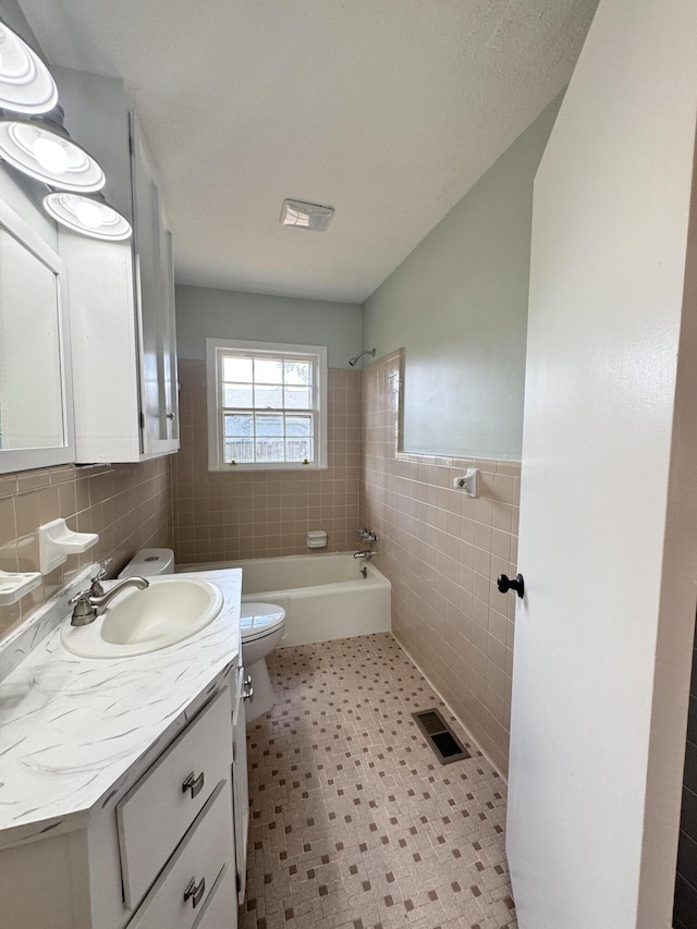 full bathroom with vanity, toilet, tub / shower combination, and tile walls