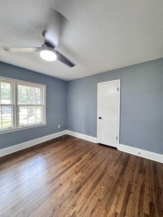 empty room with ceiling fan, wood-type flooring, and a textured ceiling