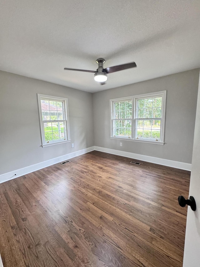 spare room featuring ceiling fan, dark wood-type flooring, and a textured ceiling