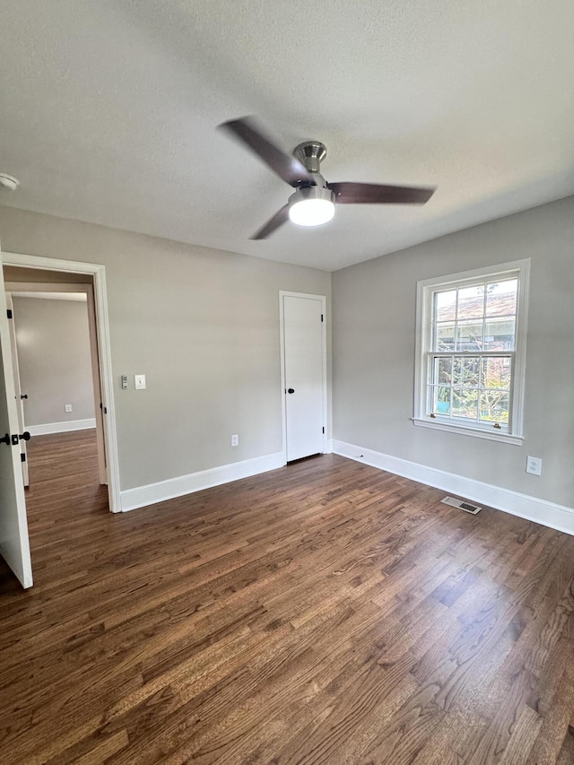 unfurnished bedroom featuring ceiling fan, dark hardwood / wood-style floors, and a textured ceiling