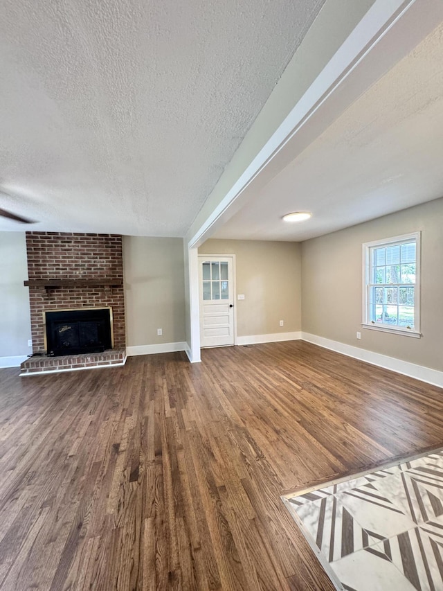 unfurnished living room with a fireplace, wood-type flooring, and a textured ceiling