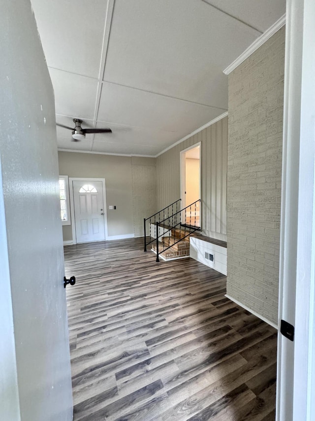 foyer entrance featuring brick wall, ornamental molding, and hardwood / wood-style floors