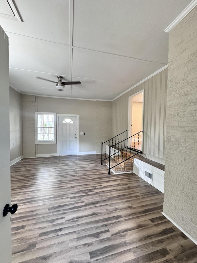 foyer entrance featuring crown molding, wood-type flooring, ceiling fan, and brick wall