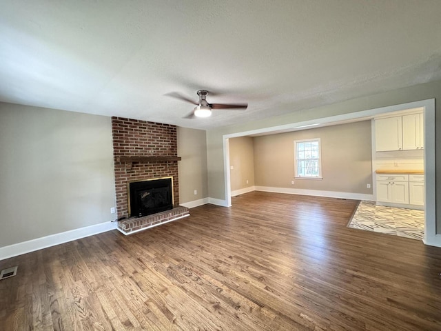 unfurnished living room featuring hardwood / wood-style flooring, a fireplace, a textured ceiling, and ceiling fan