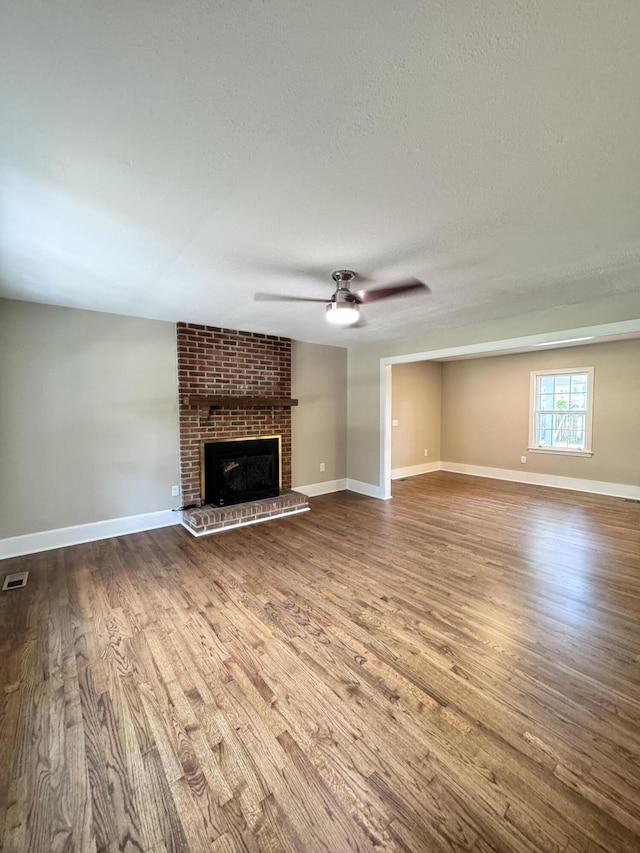 unfurnished living room featuring ceiling fan, hardwood / wood-style floors, a textured ceiling, and a fireplace