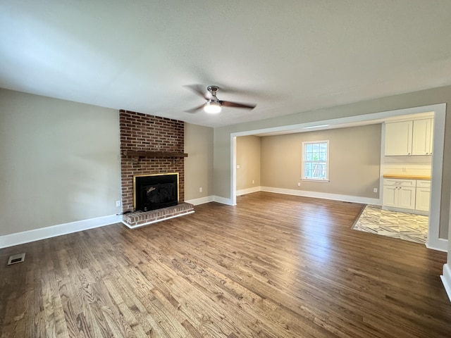 unfurnished living room featuring hardwood / wood-style flooring, ceiling fan, and a brick fireplace