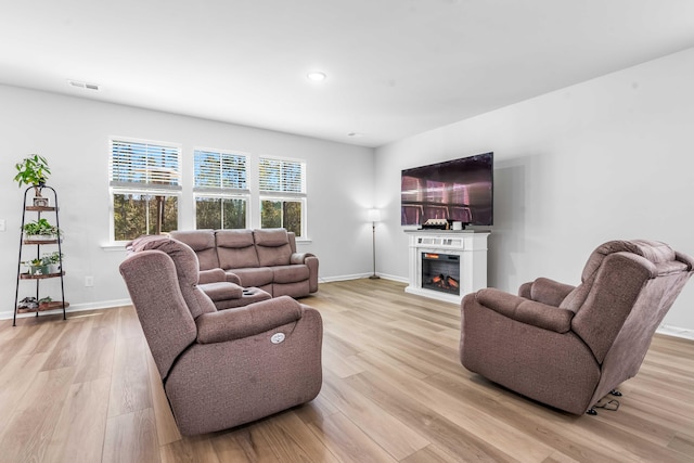 living room with visible vents, baseboards, recessed lighting, light wood-style floors, and a glass covered fireplace