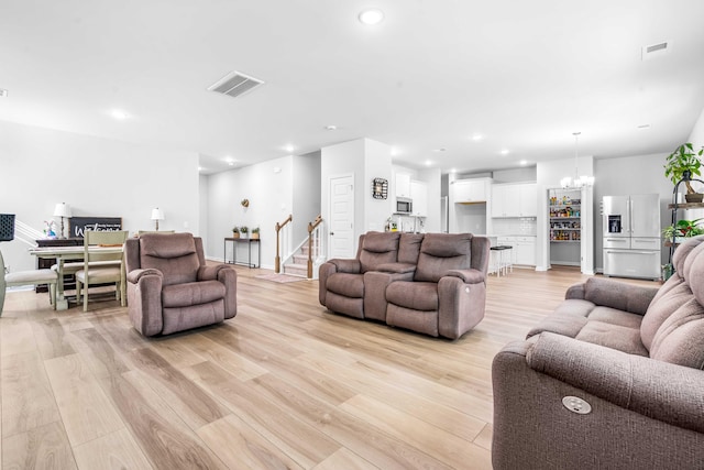 living room with visible vents, recessed lighting, stairs, a notable chandelier, and light wood-type flooring