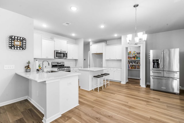 kitchen featuring light wood finished floors, visible vents, a kitchen breakfast bar, stainless steel appliances, and a sink