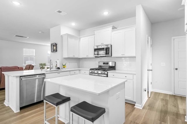 kitchen featuring visible vents, a sink, white cabinetry, light wood-style floors, and appliances with stainless steel finishes