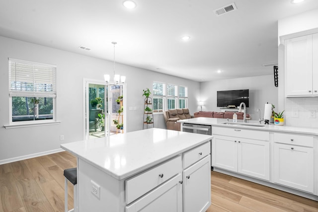 kitchen with light wood-style flooring, visible vents, backsplash, and a sink