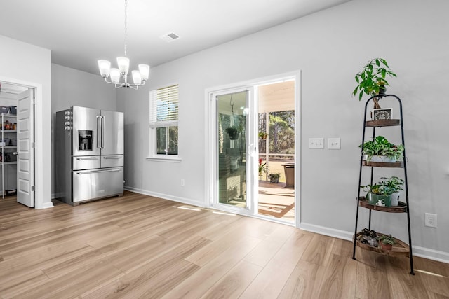 unfurnished dining area with visible vents, baseboards, a notable chandelier, and light wood-style flooring