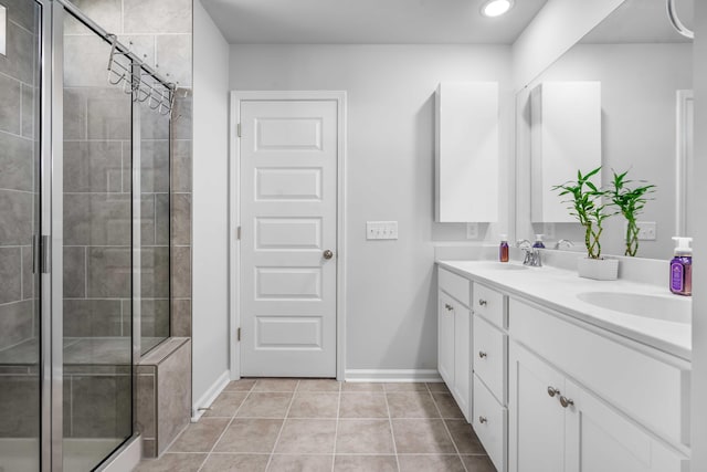 full bathroom with baseboards, double vanity, a stall shower, a sink, and tile patterned flooring