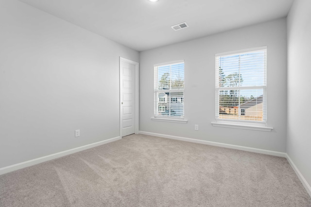 unfurnished room featuring light carpet, visible vents, and baseboards