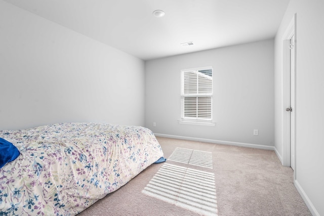 bedroom featuring visible vents, light colored carpet, and baseboards