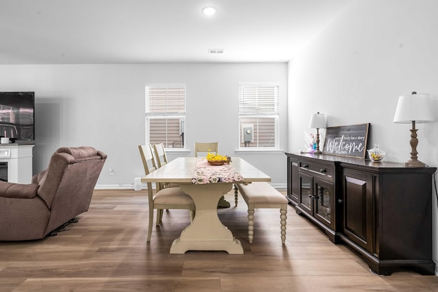 dining area with visible vents, baseboards, recessed lighting, light wood-style flooring, and a glass covered fireplace