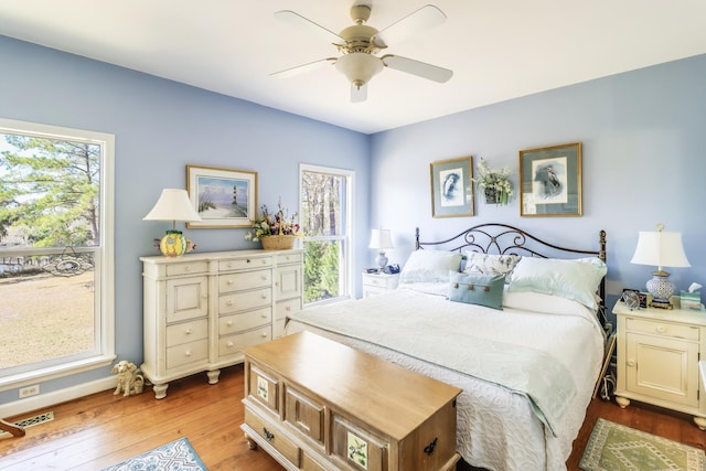 bedroom with baseboards, a ceiling fan, visible vents, and light wood-style floors