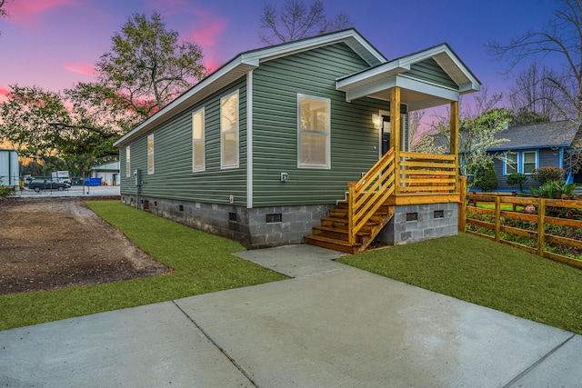 view of front of home with a yard, fence, and crawl space