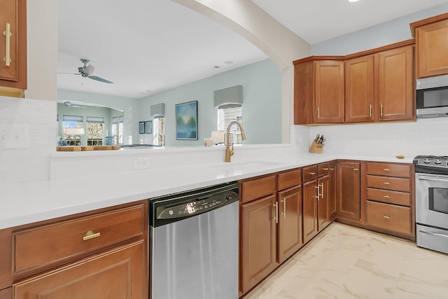 kitchen with appliances with stainless steel finishes, sink, ceiling fan, and kitchen peninsula