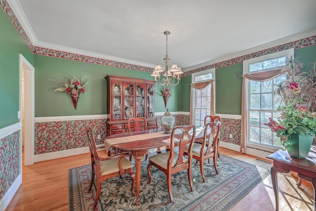 dining space featuring light wood-type flooring, ornamental molding, and an inviting chandelier