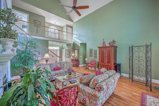 living room featuring a high ceiling, light hardwood / wood-style floors, and ceiling fan