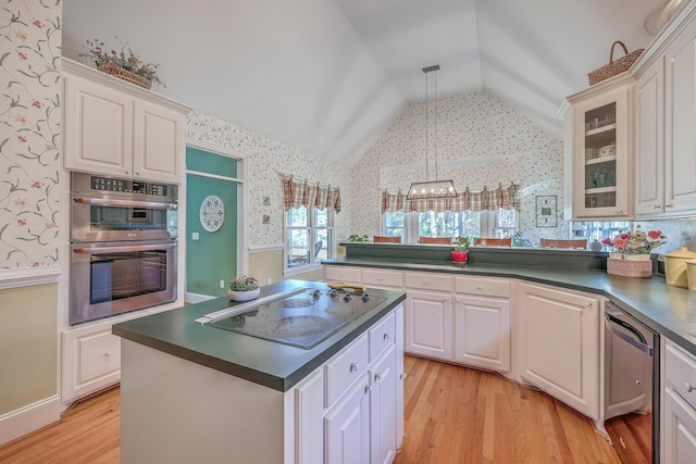 kitchen with white cabinets, light wood-type flooring, hanging light fixtures, and appliances with stainless steel finishes