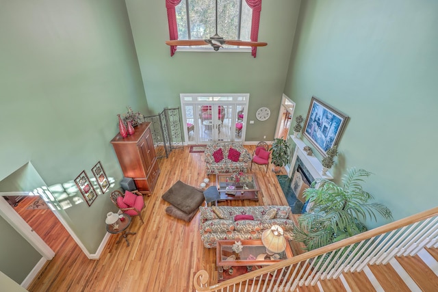 living room featuring wood-type flooring, a towering ceiling, and ceiling fan